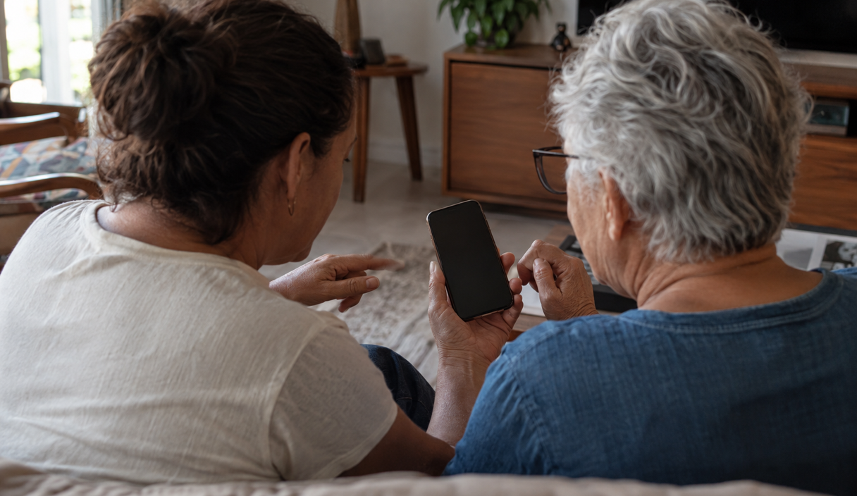 Pessoa adulta e familiar mais velho conversam juntos sobre uma mensagem no celular
